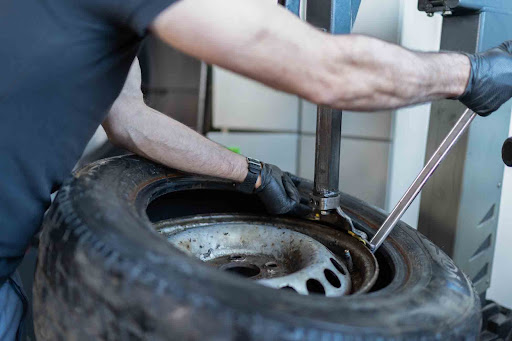 Man pulling aluminum rim off of a tire to recycle it